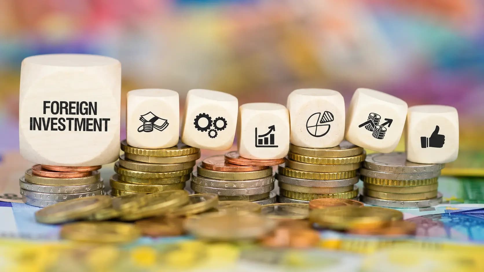 Wooden blocks reading 'FOREIGN INVESTMENT' arranged with icons for growth, strategy, and finance atop stacks of coins, representing international investment in Türkiye.
