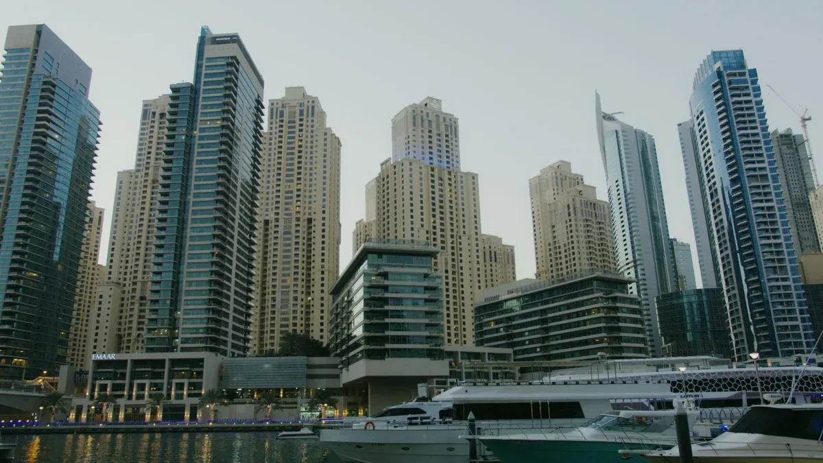 High-rise residential buildings along a waterfront with two white yachts in the foreground.
